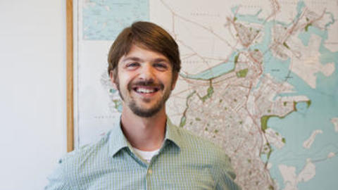 Dan O'Brien in front of a wall-mounted map of boston