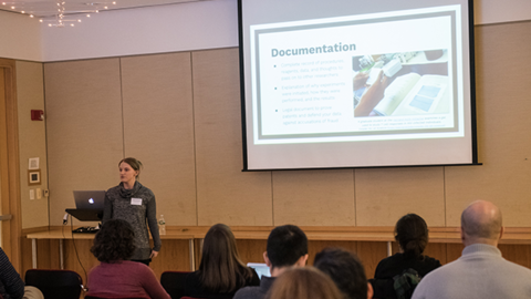 Conference speaker with projected presentation and audience
