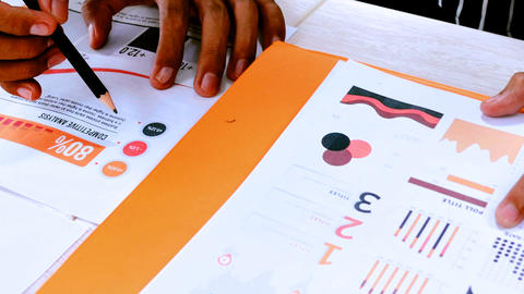close up of hands on printed graphs and charts