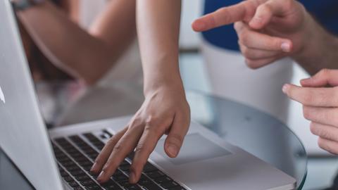 Closeup of multiple people interacting with a laptop