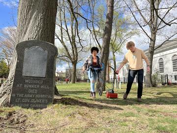Aja Lans and Andrew Bair roll a mapping device through the Cambridge Old Burying Ground