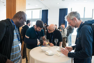 A conference attendee shows information on his phone to other attendees