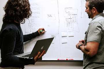 Two people working at a whiteboard