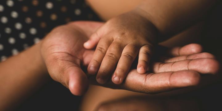 Close-up of baby hand in the palm of an adult hand