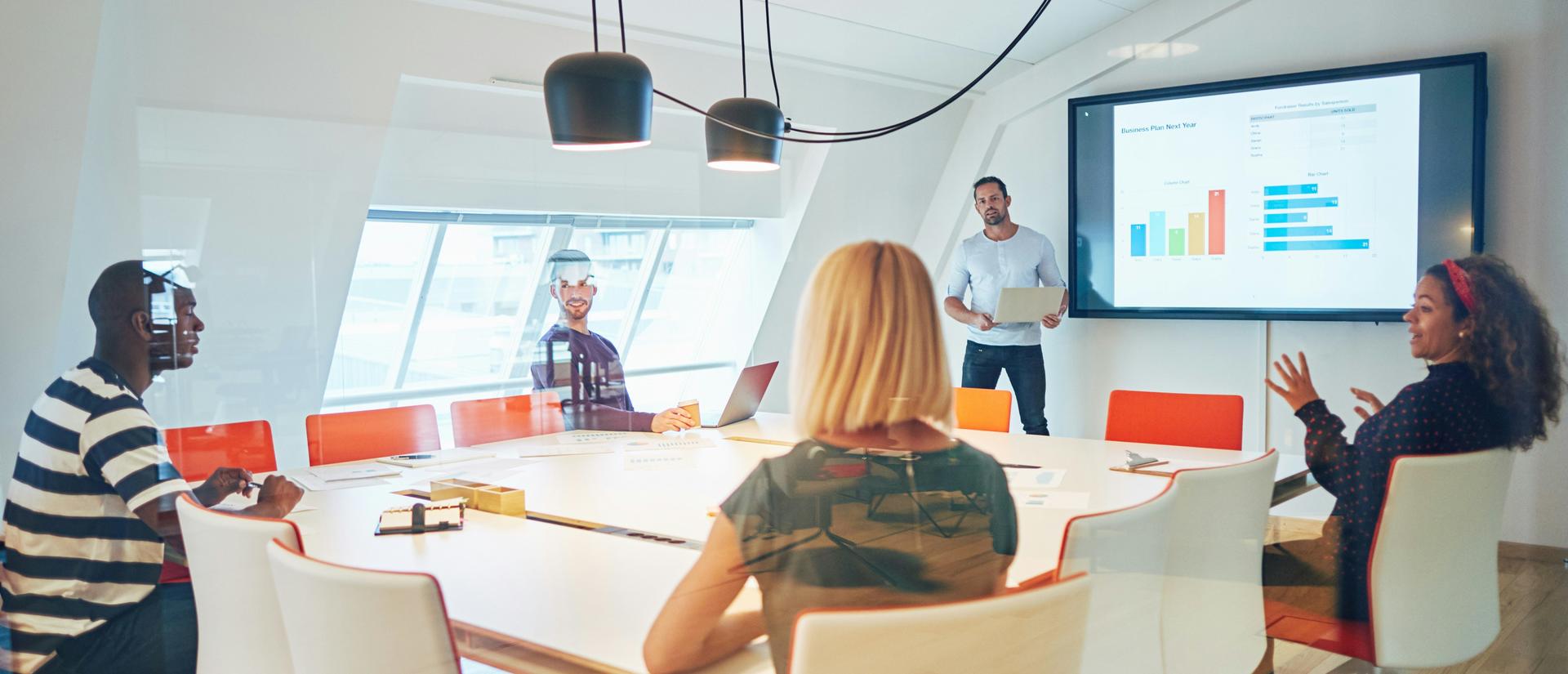 Small group meeting and discussing a data chart being presented on a screen